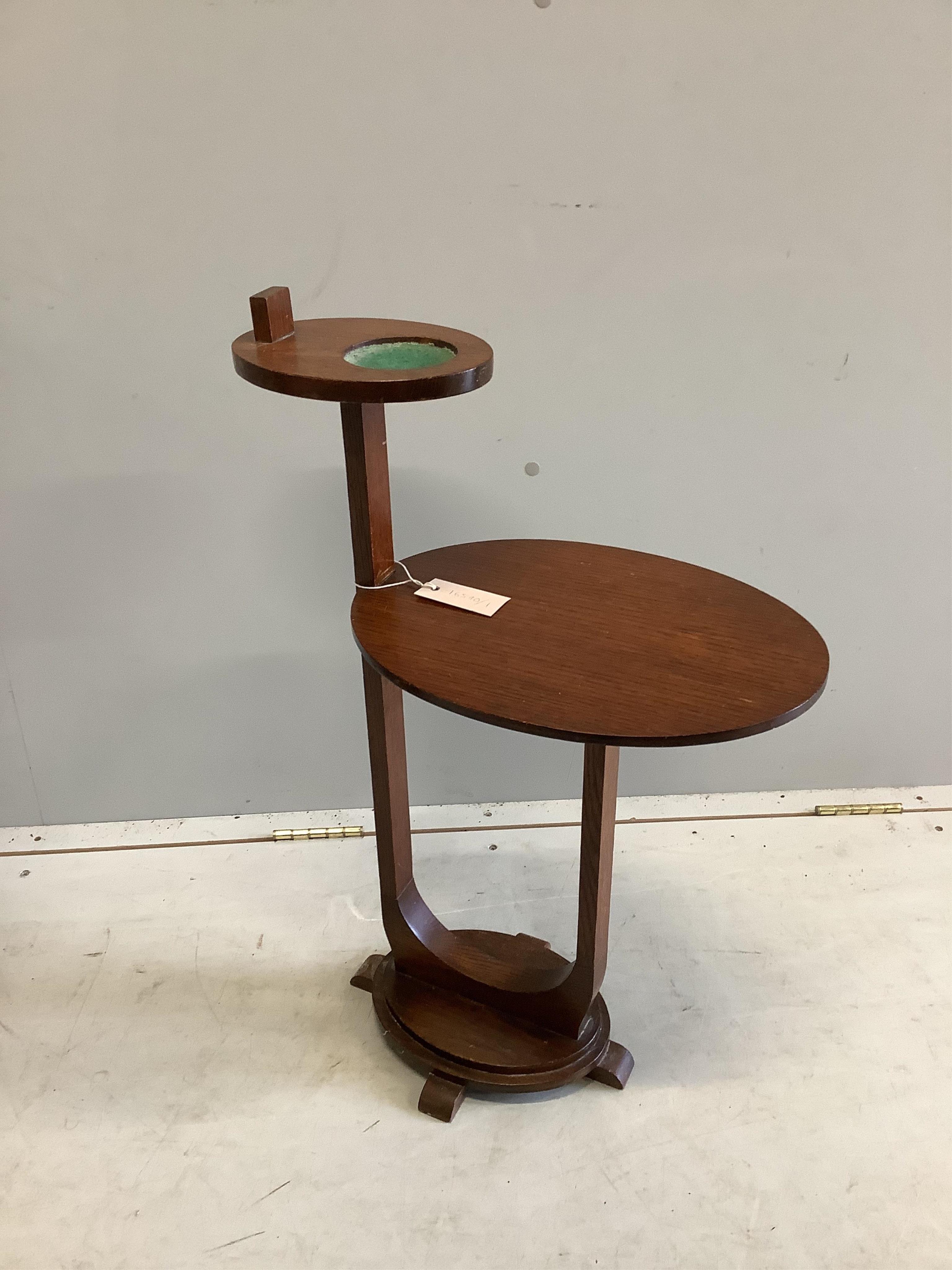 An early 20th century Liberty style circular oak occasional table, diameter 60cm, height 72cm. Condition - fair, top water stained together with a two tier smokers stand.